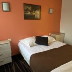 double bed with orange decoration - appart hotel bretagne bord de mer
