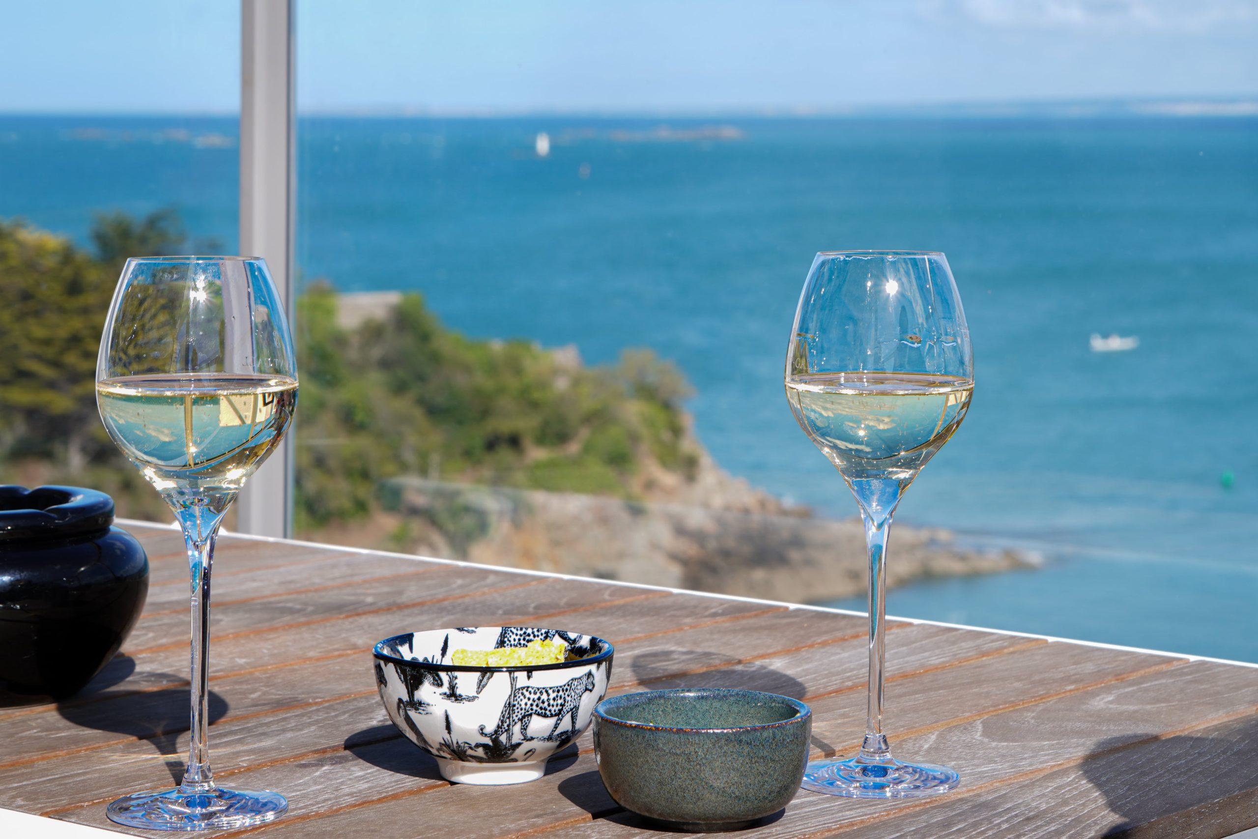 Two glasses of white wine on a table facing the sea in fine weather